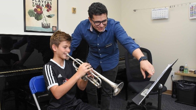 teaher helping student play trumpet